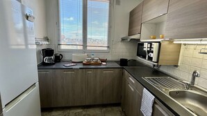 Una cocina compacta con ventana, microondas, pileta y cafetera.