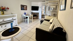 Una sala de estar con sofá, mesa de comedor, televisor y chimenea.