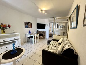 Ein Wohnzimmer mit einer Couch, einem Esstisch, einem Fernseher und einem Kamin.