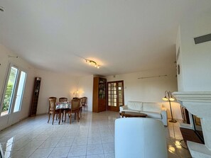 A spacious living area with a dining table, chairs, a sofa, and a fireplace. - Charming house - 4 guests, near beach (La Brée-les-Bains)