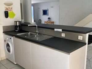 Eine moderne Küche mit Einbauwaschmaschine, Spüle und Kaffeemaschine.