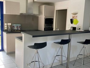 Eine moderne Küche mit einer zentralen Kochinsel, Barhocker und einer Mikrowelle.