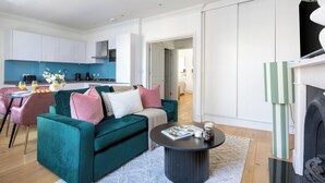 A modern living room with a teal sofa, a coffee table, and a fireplace. - Bright 1BR Near Piccadilly Circus (London)