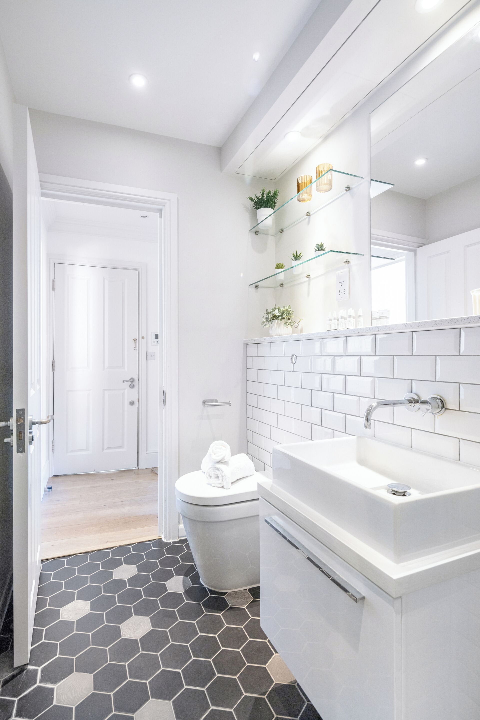 A modern bathroom with a white sink, toilet, and hexagonal patterned floor.