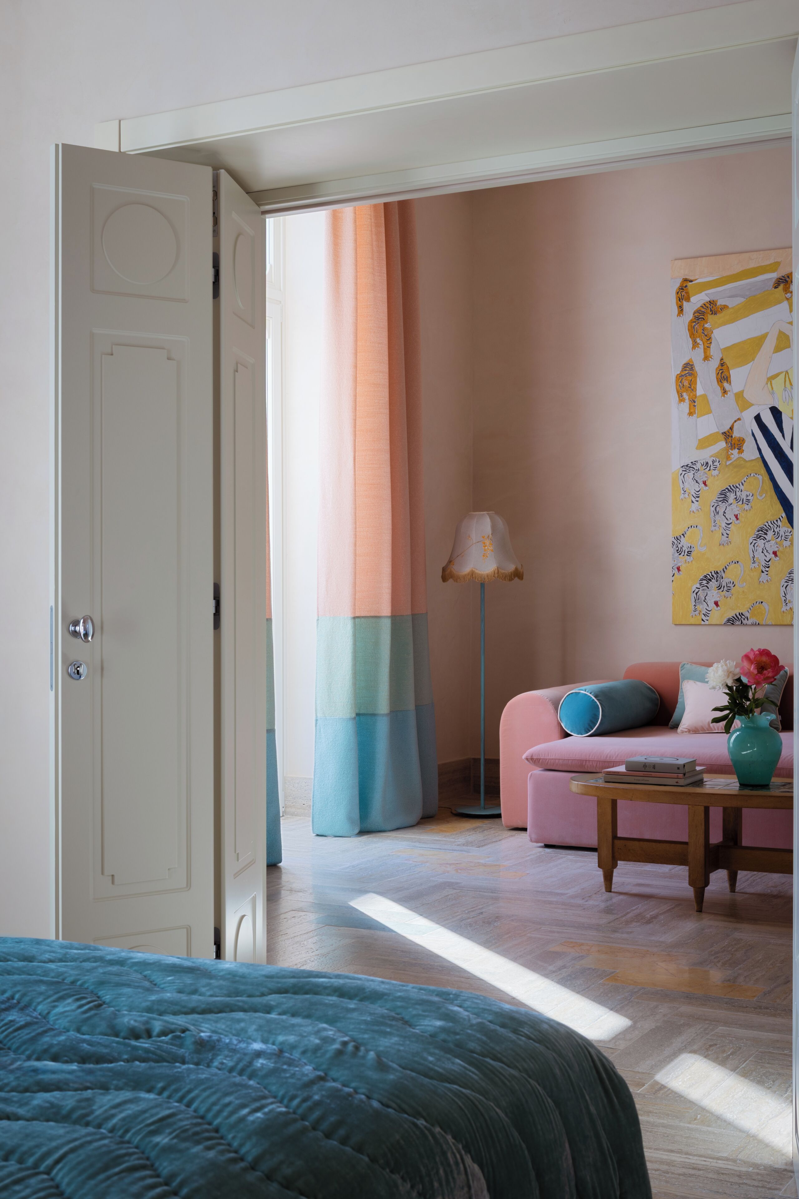 Un dormitorio con una cama, un sofá rosa, una lámpara y un cuadro en la pared.