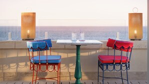 A terrace with a table and two chairs, overlooking a body of water.