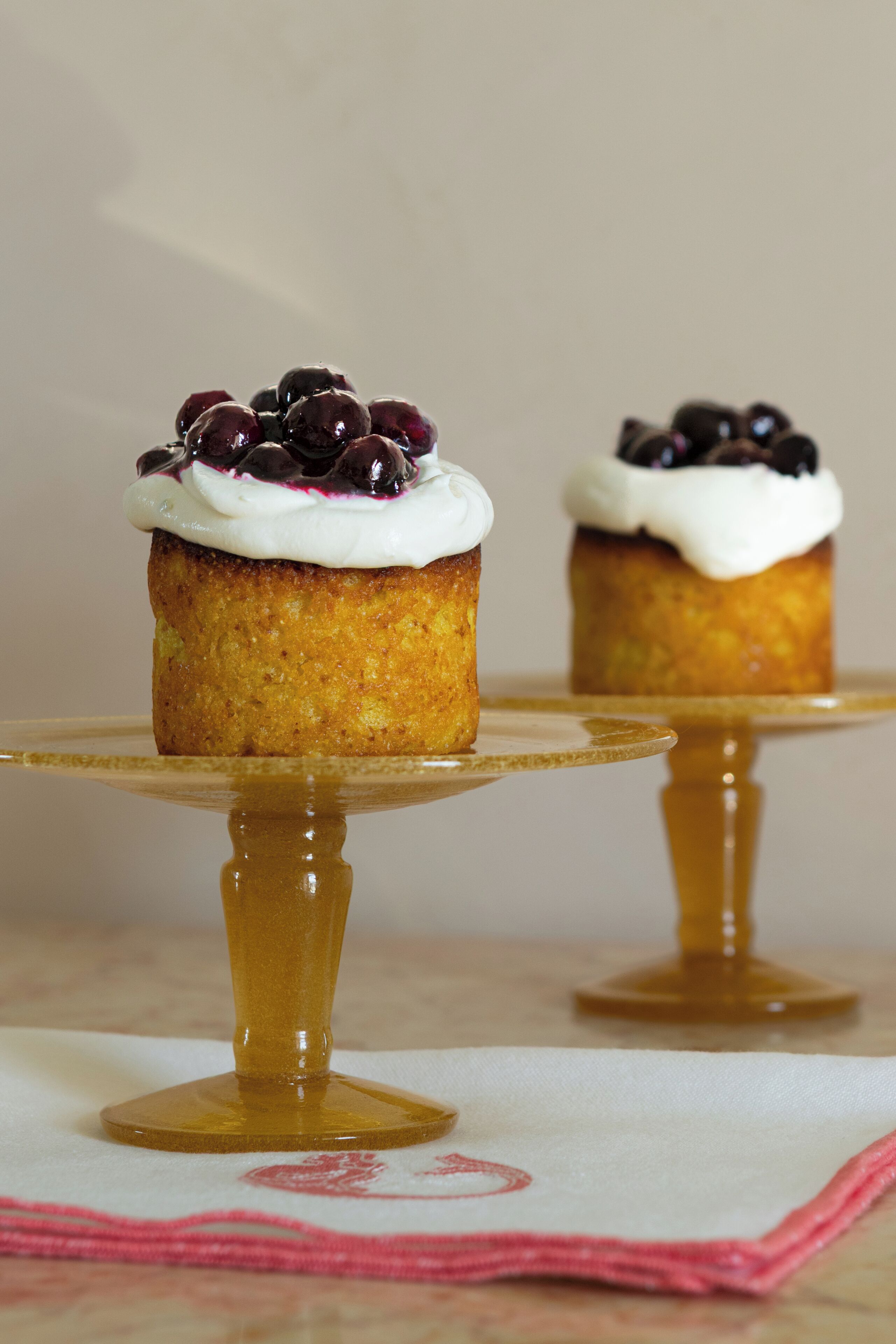 Two cupcakes on a golden stand with a white base.
