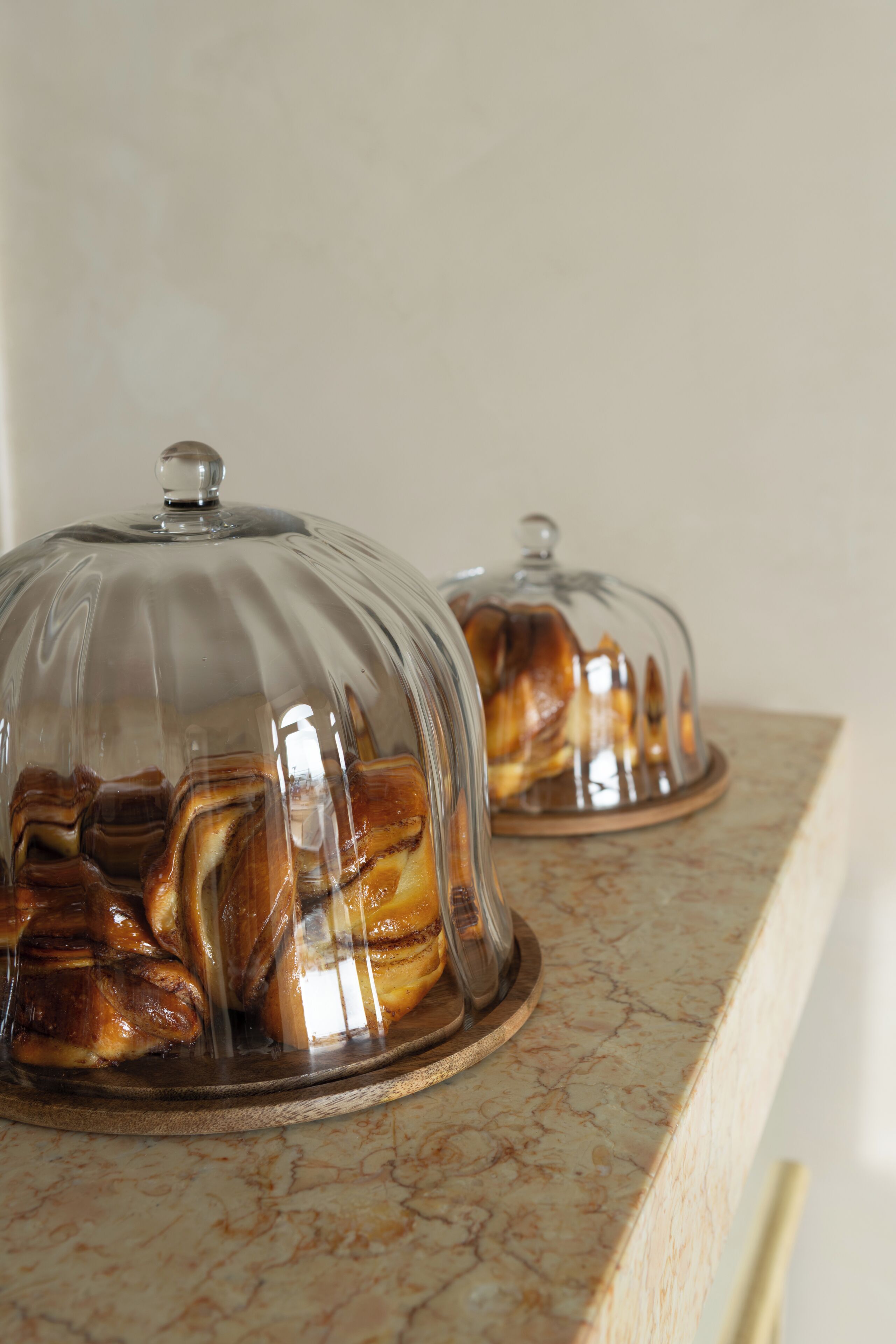 Two glass-covered food displays on a marble countertop.
