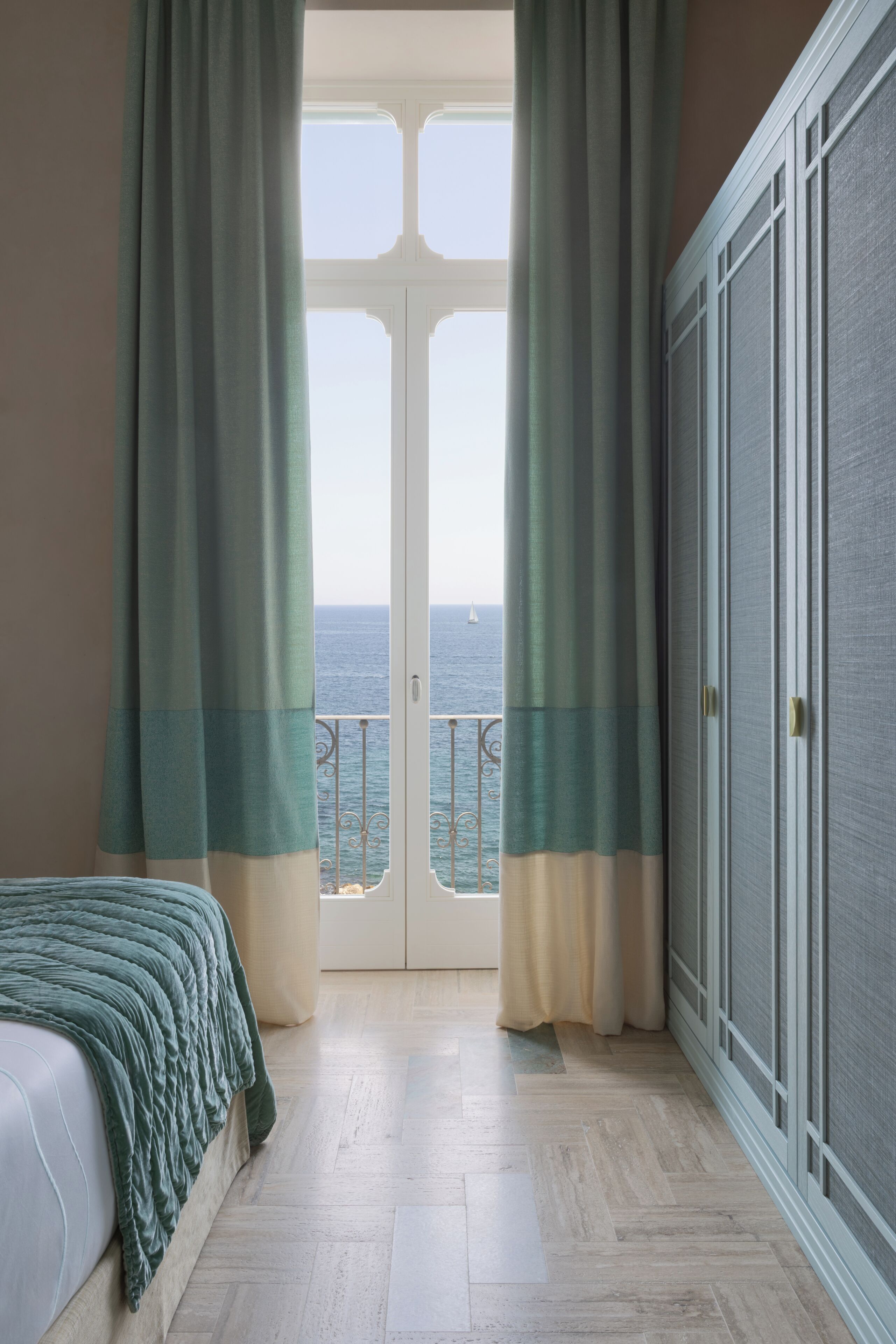 Un dormitorio con cama, vista al mar a través de una puerta y un armario.