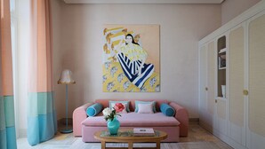 A room with a pink sofa, a wooden coffee table, and a painting on the wall.