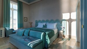 A bedroom with a bed, a sofa, a nightstand, and a window.