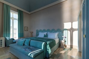 A bedroom with a bed, a sofa, a nightstand, and a window. - EGEO - Ortigia (Syracuse)