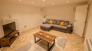 Una sala de estar con televisor, sofá y mesa de centro.