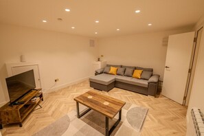 A living room with a TV, sofa, and coffee table. - Modern Newly Converted  Retreat with Hot Tub - Rye (East Sussex)