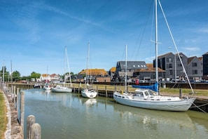 A marina with several sailboats docked, a wooden jetty, and buildings in the background. - Modern Newly Converted  Retreat with Hot Tub - Rye (East Sussex)