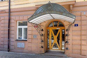 Ein Hotel Eingang mit Vordach, einer großen Holztür und der Zahl '8' an der Wand.