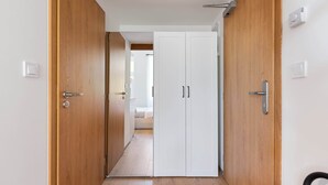 A hallway with wooden doors, a white wardrobe, and a bed in the background. - Lovely studio in the center city (Hlavní město Praha)