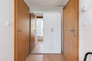 Ein Flur mit Holztüren, einem weißen Schrank und einem Bett im Hintergrund.