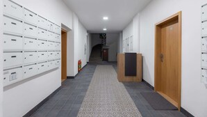 A hallway with storage lockers, a wooden reception desk, and a staircase in the background. - Lovely studio in the center city (Hlavní město Praha)