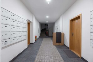 Ein Flur mit Ablagekörben, einem hölzernen Empfangstresen und einer Treppe im Hintergrund.