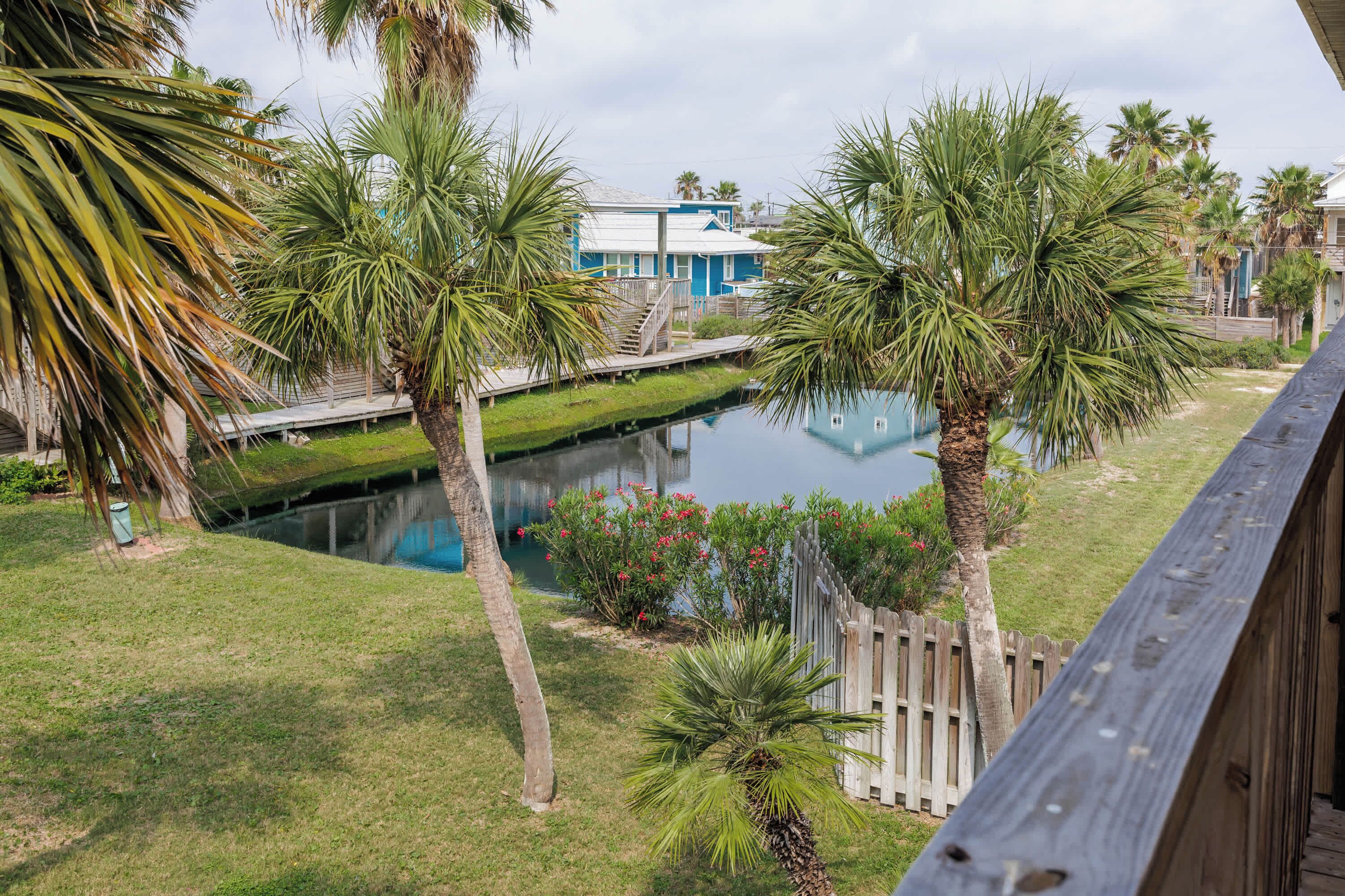 Un quartier résidentiel agrémenté d’un élément aquatique, de palmiers et d’une maison bleue avec un quai.