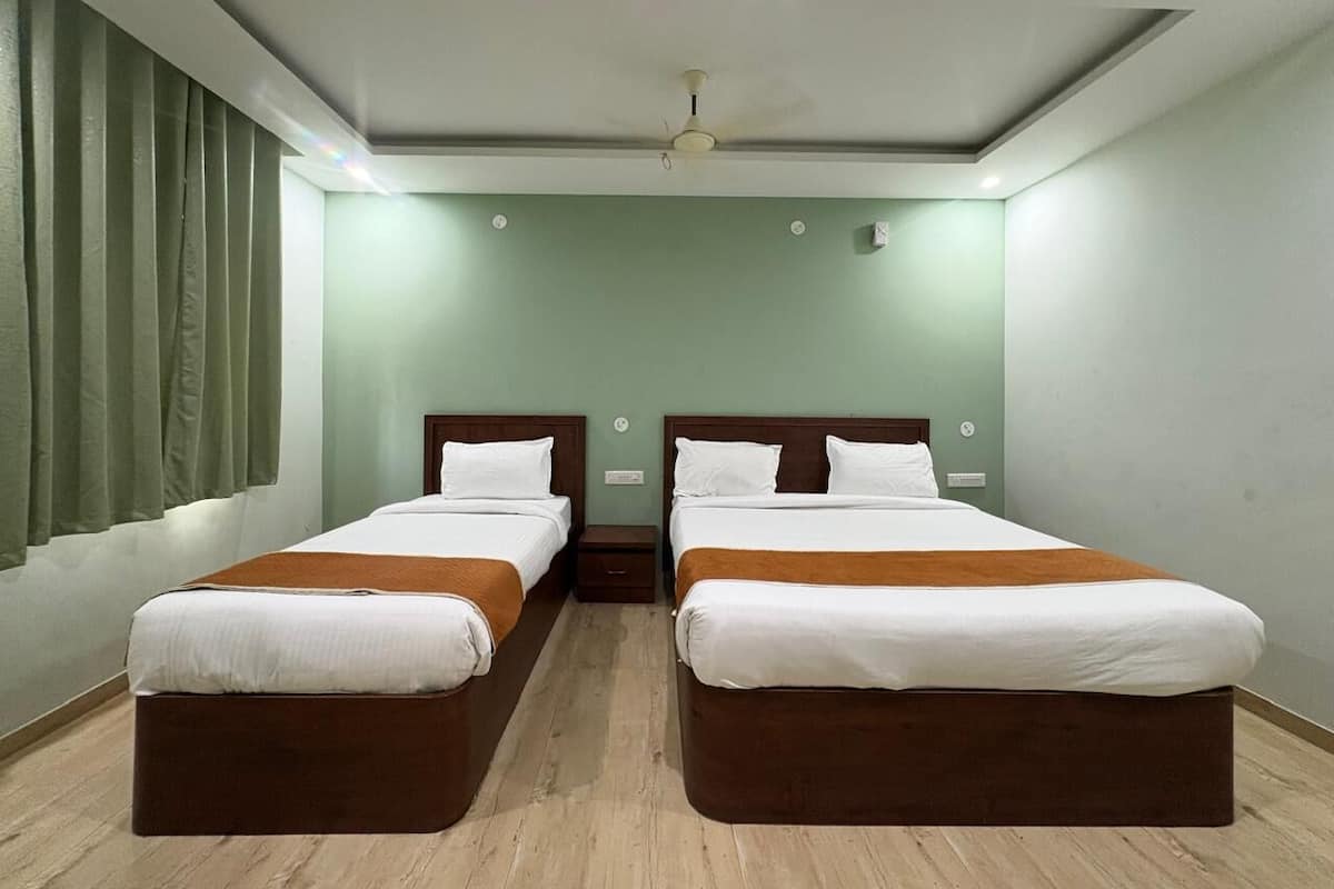 Habitación de hotel con dos camas, ventilador de techo y ventana con cortinas.