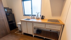 Cocina pequeña con microondas, lavabo y cafetera.