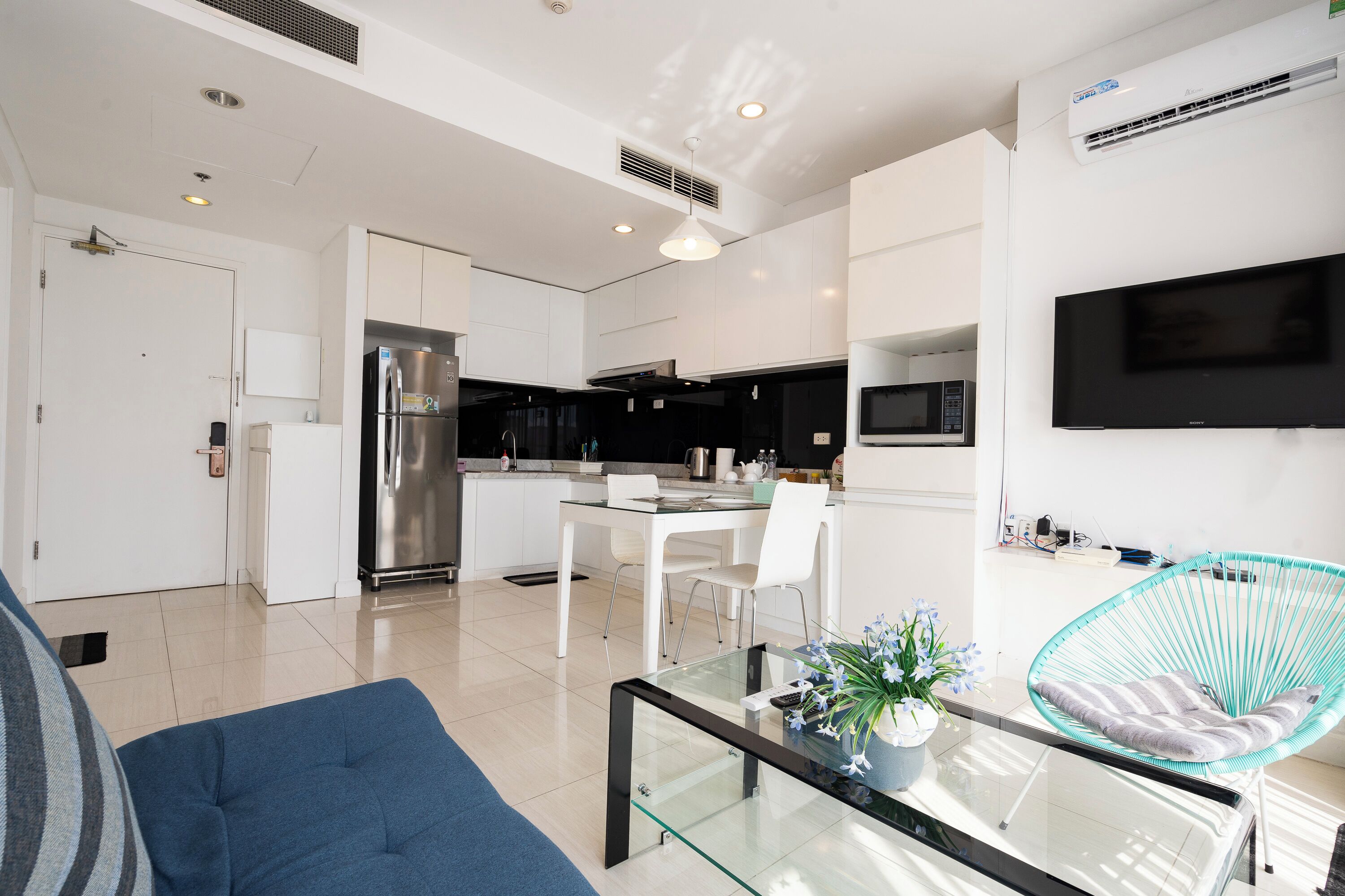 A modern kitchen with a refrigerator, microwave, and dining area.