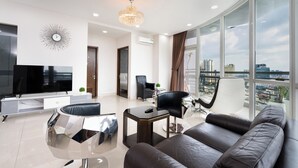 A modern living room with a large flat-screen TV, a sofa, a coffee table, and a chandelier. - Tracy Ben Thanh Tower  (Ho Chi Minh City)