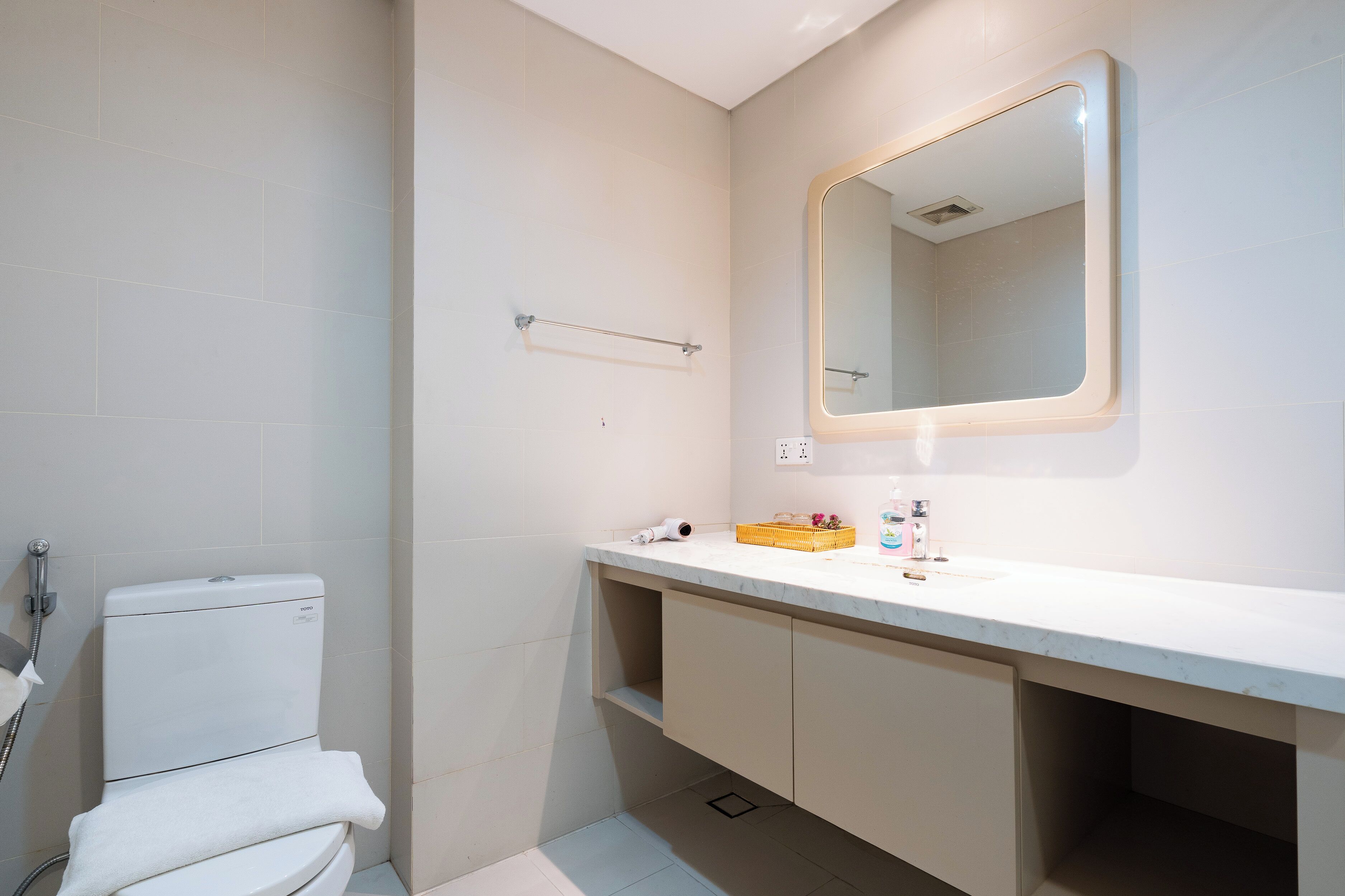 A bathroom with a toilet, a sink, a mirror, and a towel rack.