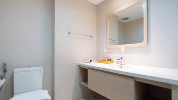 A bathroom with a toilet, a sink, a mirror, and a towel rack.