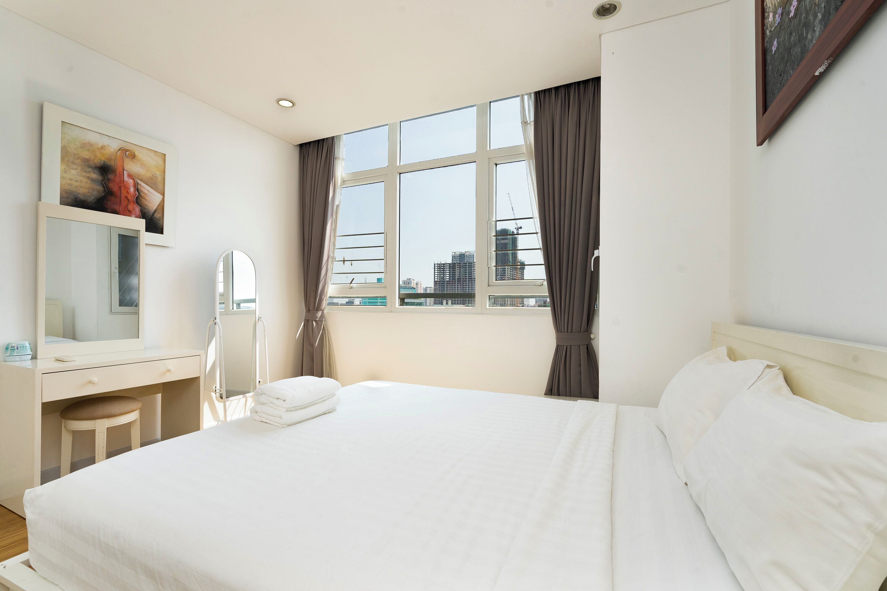Een hotelkamer met een bed, bureau, stoel, spiegel en een raam met gordijnen.