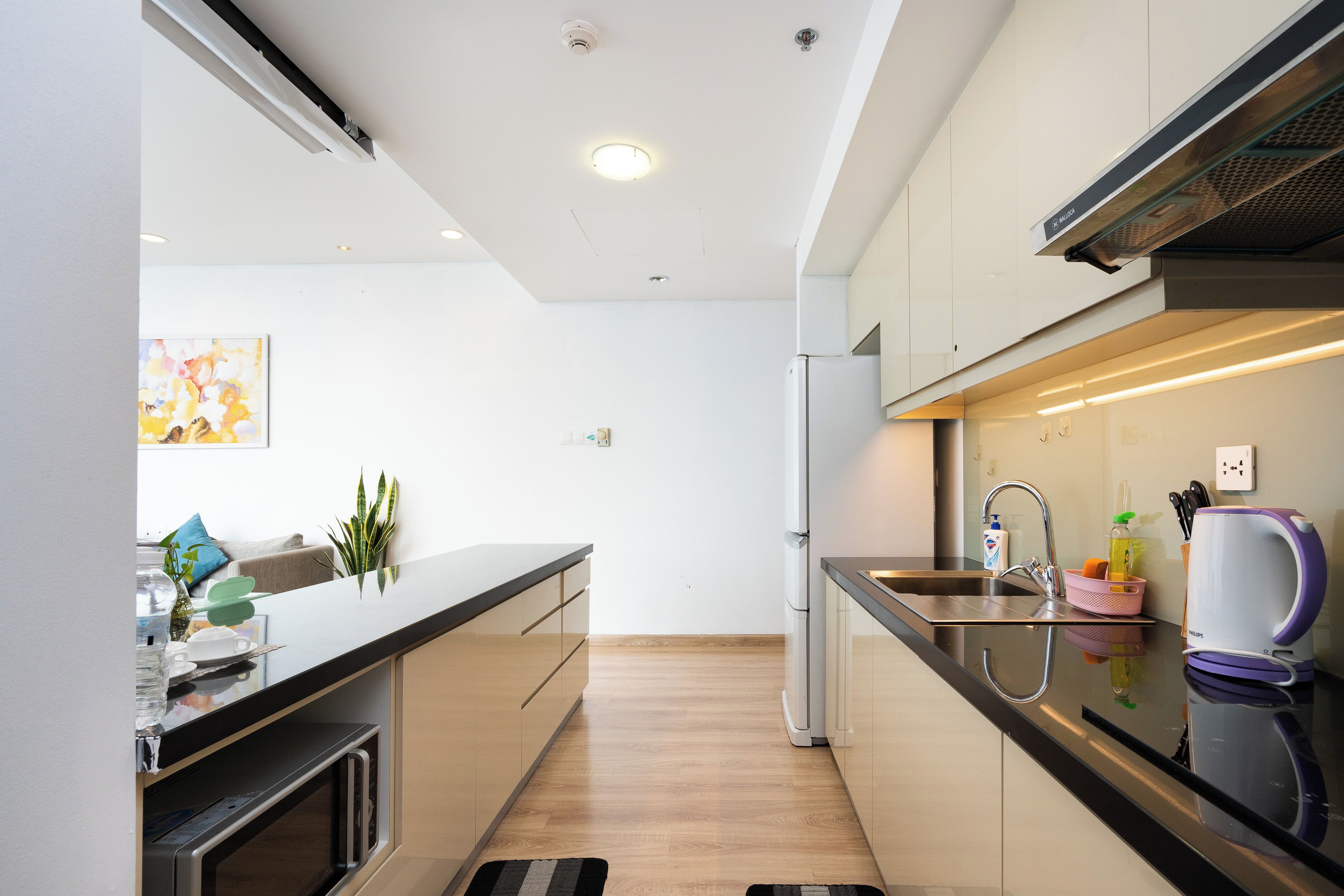A modern kitchen with a stainless steel refrigerator, a sink, and a coffee maker.