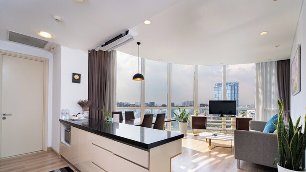 A modern living room with a kitchen island, large windows, and a city view. - Tracy Ben Thanh Tower  (Ho Chi Minh City)
