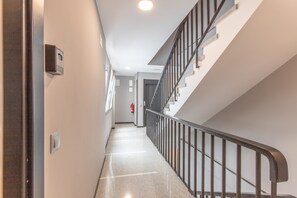 A hallway with a staircase, a fire alarm, and a door on the left. - Vacation Apartment 'Casita Sunwaves' with Sea View, Wi-Fi and Air Conditioning (Las Palmas de Gran Canaria)