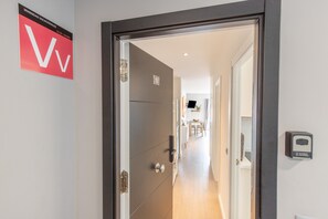 En hotellentrédörr, en skylt med texten ”VIVIENDA VACACIONAL” och ett nummer, samt en kontrollpanel på väggen.