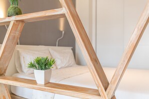 A wooden ladder with a potted plant on a white bed with a gray wall in the background. - Vacation Apartment 'Casita Sunwaves' with Sea View, Wi-Fi and Air Conditioning (Las Palmas de Gran Canaria)