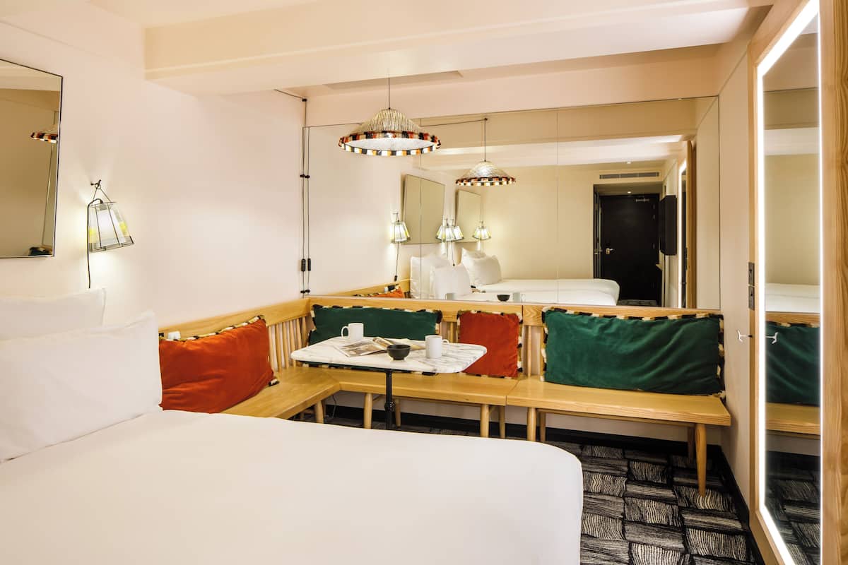 A hotel room with a bed, a seating area with a table, and a large mirror.