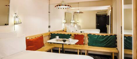 A hotel room with a bed, a seating area with a table, and a large mirror.