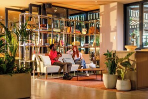 A modern interior with a sofa, a coffee table, and a bookshelf filled with books and decorative items. - ARK Shoreditch (London)