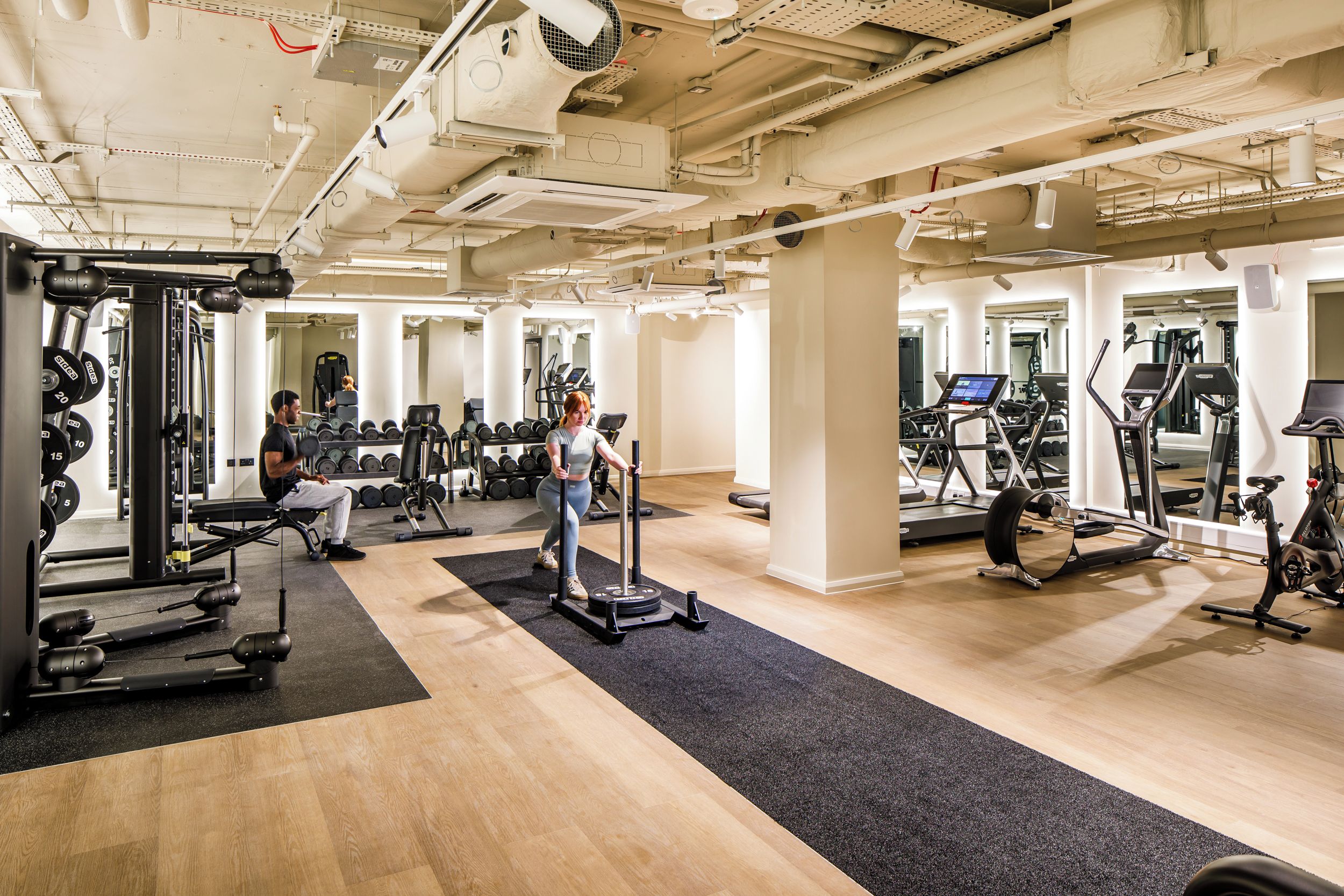A gym with various exercise equipment, including treadmills, weight machines, and free weights.