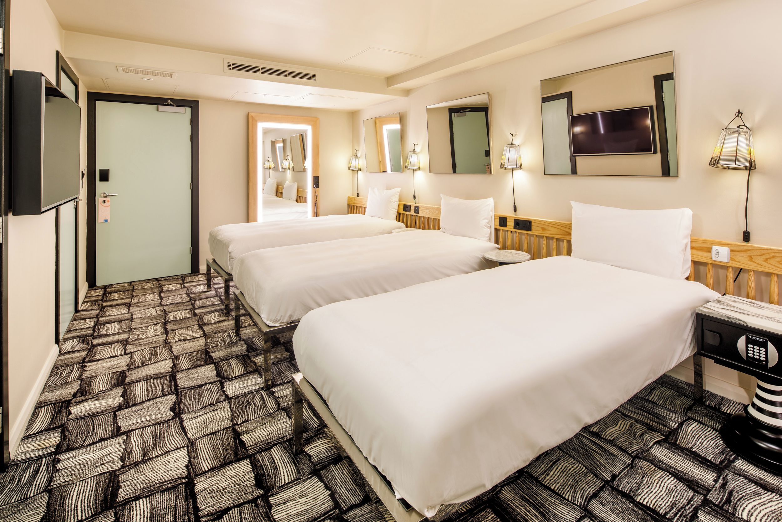 A hotel room with two beds, a flat-screen TV, a microwave, and a bathroom door.