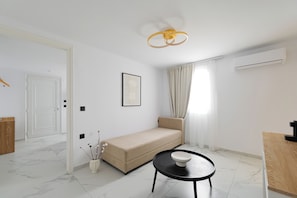 A modern, minimalist living room with a sofa, a small round table, and a pendant light.