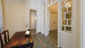 A hallway with a wooden table, a vase with flowers, and a door leading to another room. - Kismet Urban Boutique (Heraklion)