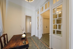 A hallway with a wooden table, a vase with flowers, and a door leading to another room.