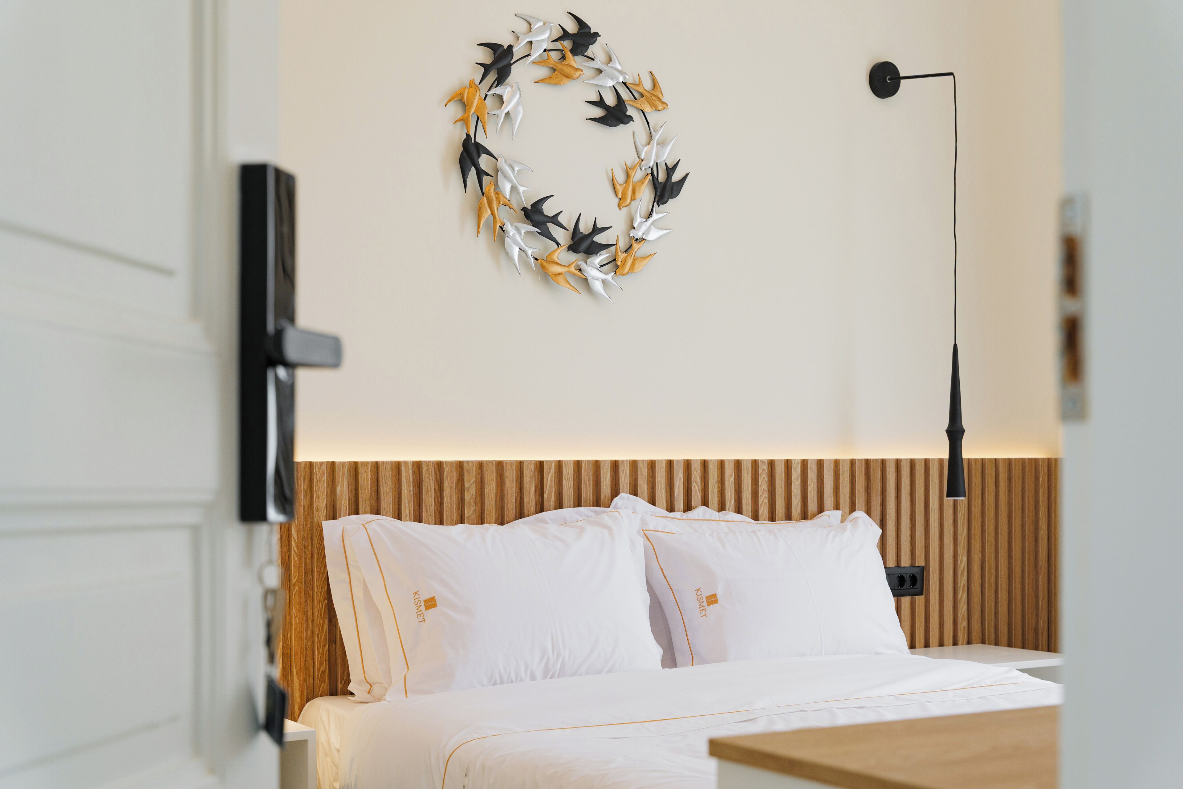 A modern bedroom with a bed, a wall-mounted light, and a decorative wreath.
