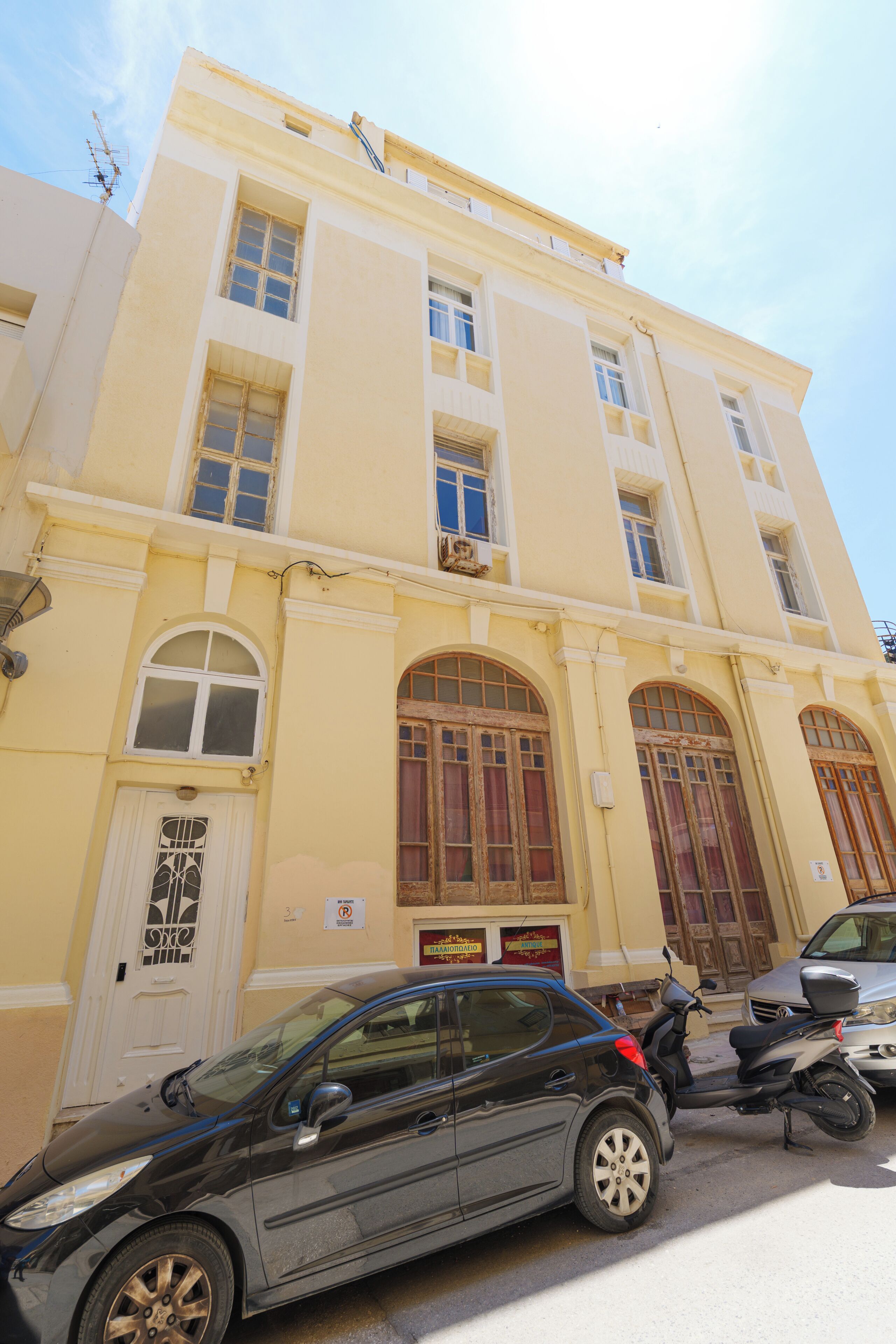 Un edificio de varios pisos con fachada amarilla, grandes ventanales de arco y una puerta blanca.