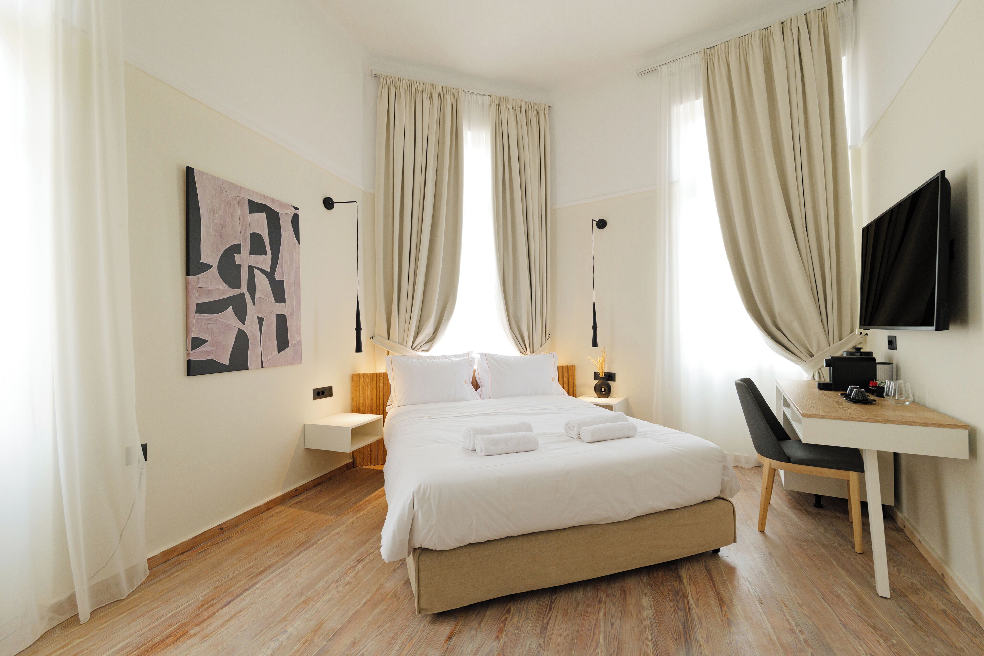 Ein modernes Hotelzimmer mit einem großen Bett, einem Schreibtisch und einem Fernseher.