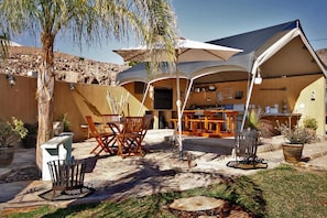 Un patio al aire libre con zona de comedor, bar y área de estar cubierta.