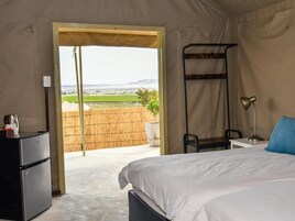 Un dormitorio con cama, escritorio, silla, lámpara y refrigerador.